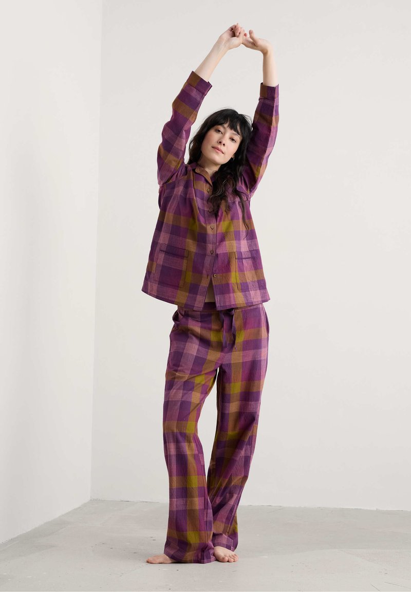 Paarse en gele geruite pyjama set met een knoopsluiting overhemd met zakken en bijpassende elastische broek, gemaakt van zachte stof.