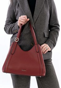 Rote strukturiert Lederhandtasche mit abgerundetem oberen Teil, zwei robusten Griffen und dezenten schwarzen Akzenten, vor einem hellen Hintergrund präsentiert.