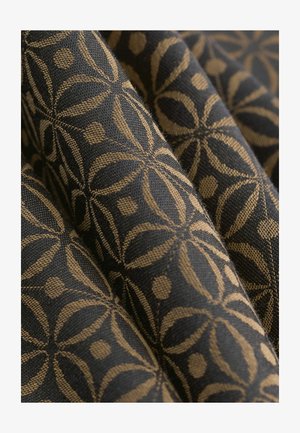 Acercamiento de una tela negra con un patrón floral geométrico dorado y una textura tejida visible, presentada en suaves pliegues.