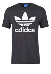 Černé bavlněné tričko s krátkými rukávy má velké bílé logo Adidas a tři vodorovné pruhy nad logem.