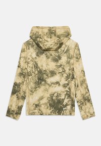 Giacca con cappuccio di base beige, caratterizzata da una stampa di foglie di palma verdi. Tessuto liscio, maniche lunghe e dettagli di cucitura lungo i bordi.