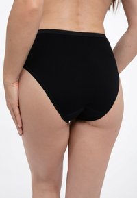 Schwarze, hochgeschnittene Unterwäsche aus weichem Stoff mit einem glatten Bund und Saumstichen, von hinten mit seitlicher Ansicht gezeigt.