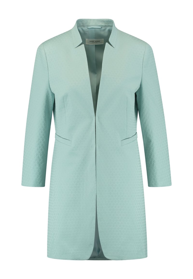 Veste bleu sarcelle clair avec un design structuré, manches 3/4, col pointu et deux poches avant. Présente une texture géométrique subtile.