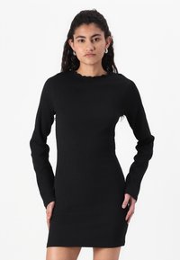 Svart langermet kjole med teksturert stoff, tettsittende design og bølgete utringning, som ender over kneet.