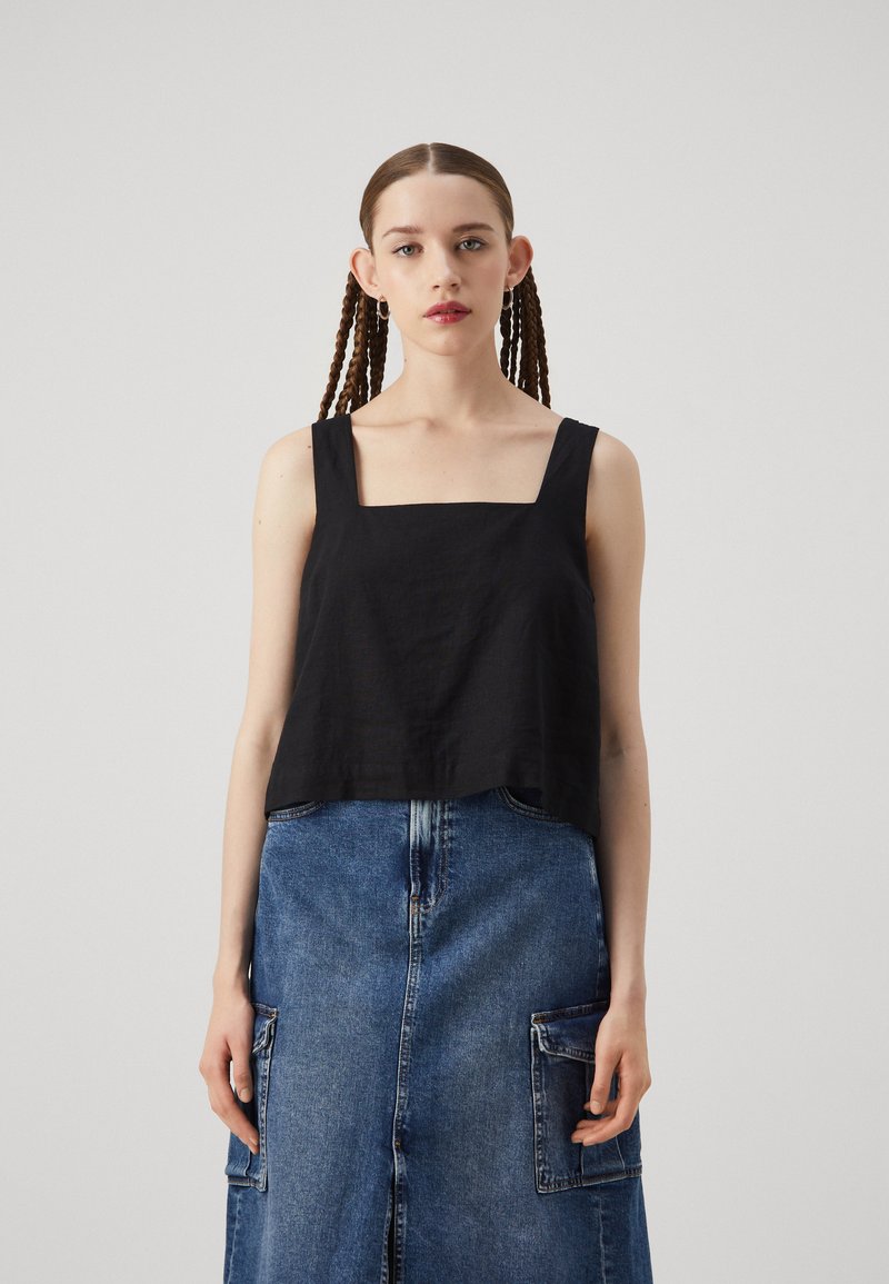 Black cropped tank top with a square neckline and thick straps, paired with a high-waisted denim skirt featuring patch pockets.