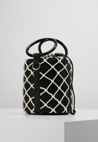 Czarna torebka z plecionym kremowym wzorem, o prostokątnym kształcie, z górnymi uchwytami i teksturowanym wykończeniem. Złote akcenty.