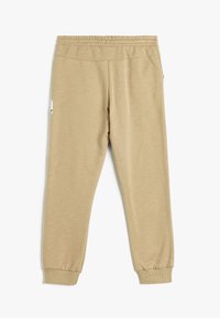 Beige joggerbroeken gemaakt van zachte stof. Elastische tailleband en boorden, met een zijzak en minimale stikdetails.