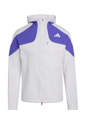Chaqueta blanca con capucha y cremallera frontal, paneles morados en los hombros y la parte superior de los brazos, y pequeño logo blanco en el pecho izquierdo.