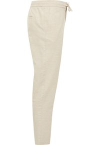Beżowe lniane spodnie dresowe z elastycznym paskiem, sznurkiem i bocznymi kieszeniami. Tkanina ma gładką fakturę i zwężany krój nogawki.