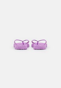 Violetti flip-flopit, joissa on kudotut tekstitetrisanget ja litteät pohjat, minimalistisella muotoilulla ja varvaskiilalla.