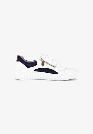 White sneaker with navy blue suede accents, brown pull tab, side zipper, and thick textured sole, shown in profile on a white background.