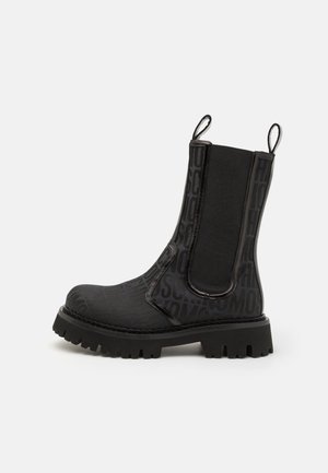 Czarne botki za kostkę z fakturowanym wierzchem ze wytłoczonym napisem, elastycznymi bocznymi panelami oraz grubą gumową podeszwą z wyraźnym bieżnikiem.