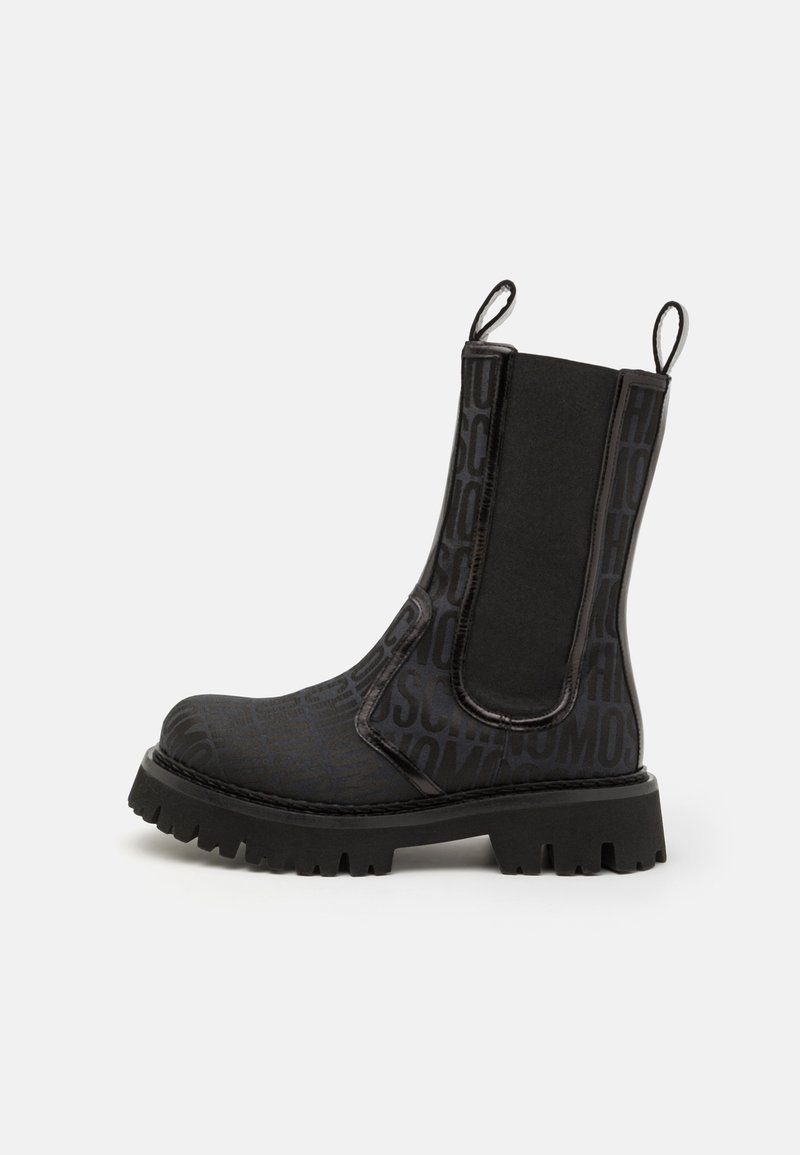 Juodos kulkšnies aulinukės su tekstūruotu paviršiumi ir iškilmingu užrašu, elastiniais šonais ir masyviu guma pagamintu padu su lygiu protektoriumi.