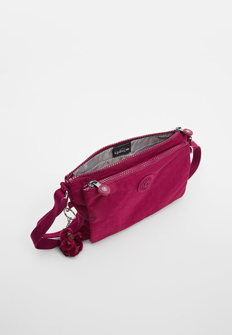 Borsa a tracolla fucsia in tessuto, con chiusura a zip, tracolla regolabile e un accento pom-pom al portachiavi. Interno foderato in grigio chiaro.