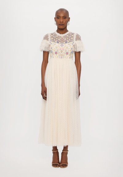 Maxi dress features a sheer floral lace bodice with ruffled short sleeves, a fitted waist, and a flowing, dotted tulle skirt in cream color.