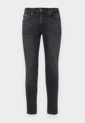 Slim-fit mustad teksased, viie tasku ja nööbi- ning tõmblukuga, esitlemine lihtsal valgel taustal.