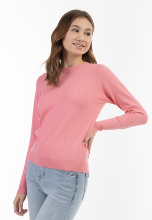 Maglione a maglia rosa chiaro con maniche lunghe, scollo a giro, polsini e orlo a coste, indossato con jeans in denim azzurro chiaro. Texture morbida, vestibilità casual.