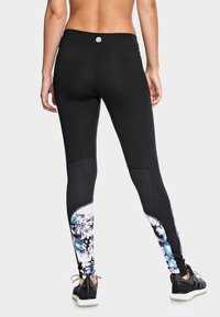 Černé legíny vyrobené z elastického materiálu, s mnohobarevným květinovým potiskem na dolní části nohou a přiléhavým střihem s vysokým pasem.