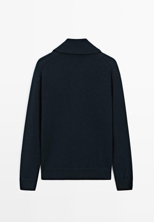 Mørk marinblå langærmet sweater med ribbet krave, manchetter og kant, vist fra bagsiden på en hvid baggrund.