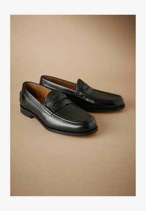 Zwarte leren instappers met geweven textuur op de punt, gladde zijkanten en subtiele stiksels. Rond gezicht en ontwerp met een lage hak.