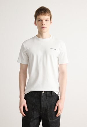 T-shirt bianca in cotone con collo rotondo, maniche corte e un piccolo logo nero "Calvin Klein" sul lato sinistro del petto.