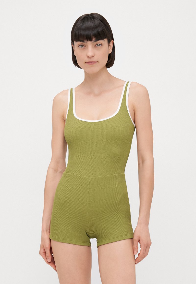 Maillot de bain une pièce vert à côtes avec un décolleté dégagé, des finitions blanches et une coupe style short. Texture lisse et design ajusté.