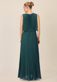 Plissé teal maxi-jurk met een mouwloos ontwerp, gelaagde top en ritssluiting aan de achterkant. Lichtgewicht stof met een luchtige textuur.