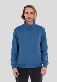 Hellblaues, glattes Zip-Jacke mit Stehkragen, elastischen Bündchen und einem Logo-Patch auf der Brust.