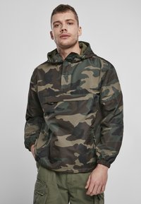 Camouflage pullover jack met capuchon, gemaakt van lichtgewicht materiaal, met elastische boorden, een voorzak en een relaxte pasvorm.