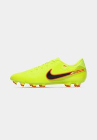 Lyse neongule fodboldstøvler med sort swoosh og detaljer, der har en struktureret overflade og orange studs til trækkraft.