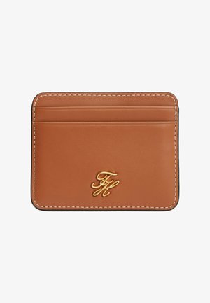 Tarjetero de cuero color marrón claro con costuras blancas, tres ranuras para tarjetas y un pequeño logo metálico dorado en el centro inferior.