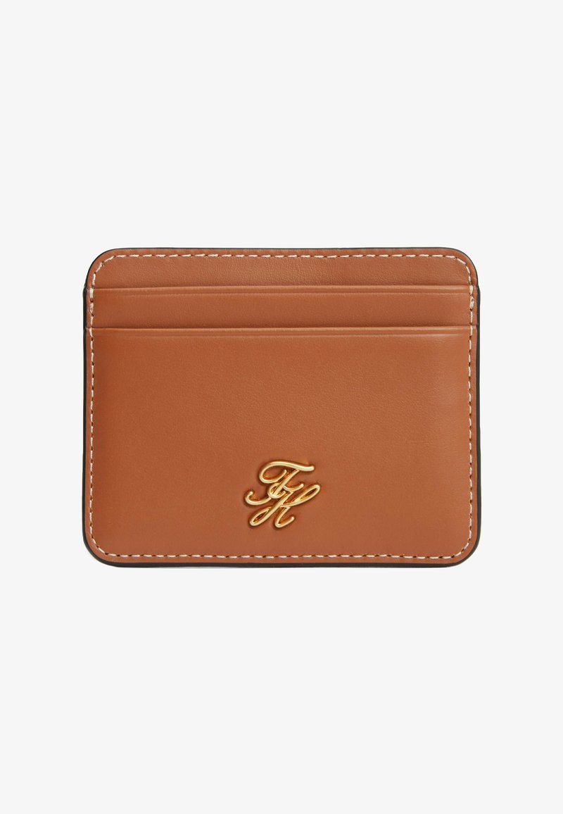 Porte-cartes en cuir fauve avec couture blanche, trois emplacements pour cartes et un petit logo en métal doré au centre en bas.