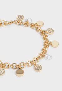 Pulsera de cadena de metal dorado que presenta charms redondos: discos lisos, un charm circular brillante y un acento de gota de cristal transparente.
