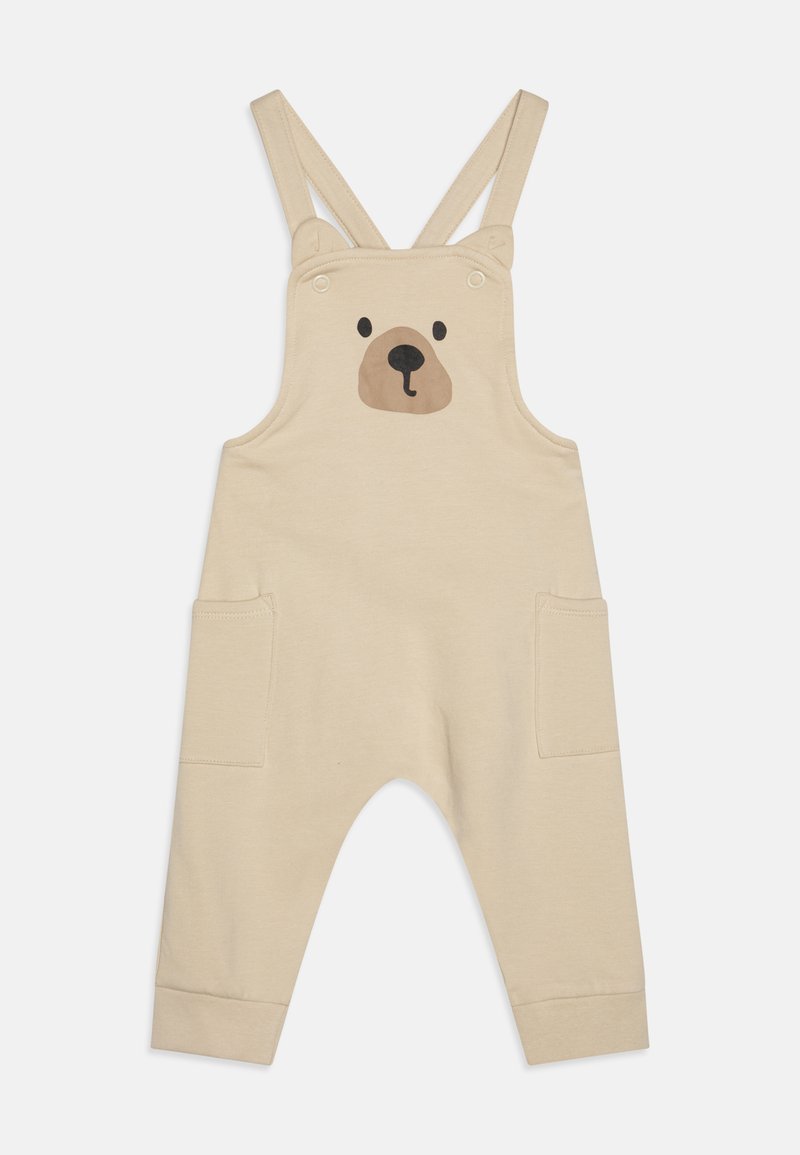 Beige overall med bjørneansigt-design på brystet, med justerbare stropper, sidelommer og manchetter ved anklerne for komfort. Glat tekstur.