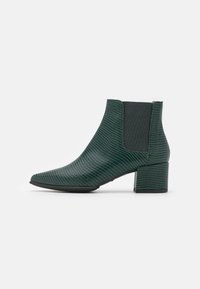 Bottine Chelsea verte avec un motif reptilien texturé, un bout pointu et un talon épais, dotée de panneaux latéraux élastiques contrastants.