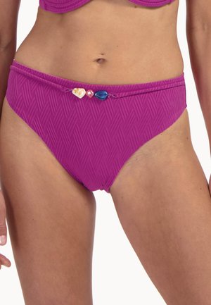 Donna che indossa slip bikini a vita alta di colore magenta con motivo diagonale testurizzato e perline decorative sulla linea della vita.
