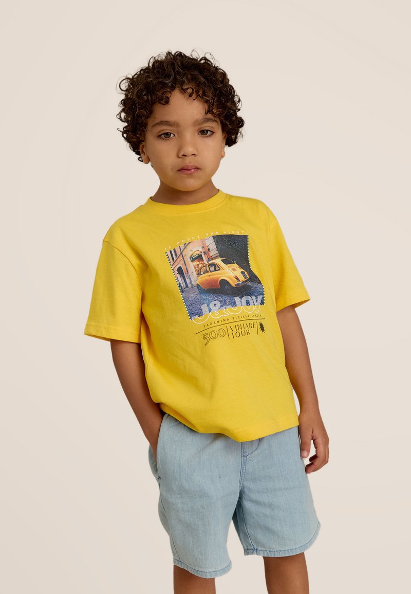 Geel katoenen T-shirt met een grafische print van een vintage gele auto en tekst. Draagt samen met lichtblauwe denimshorts.