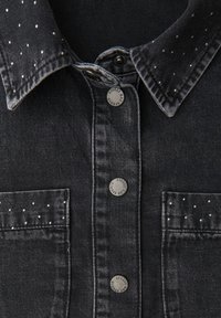 Black denim shirt featuring a speckled collar, two pockets, silver button accents, and a slightly faded wash for texture.
