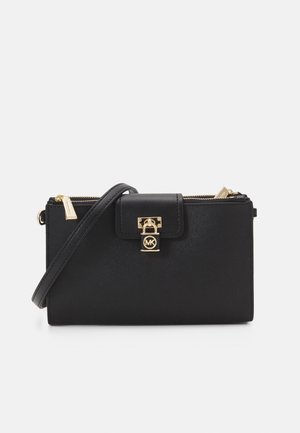 Cartera bandolera de cuero negra con cierre de candado dorado, bolsillo con cremallera y correa ajustable. Acabado texturizado y acento con el logo de MK en la parte frontal.
