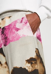 Bermudas Calvin Klein con un tejido texturizado y un patrón abstracto multicolor en tonos de rosa, marrón y beige. Detalle de bolsillo acentuado.