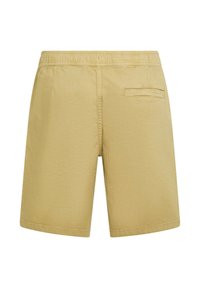 Pantalones cortos de algodón beige con cinturilla elástica, corte recto y un solo bolsillo trasero. Textura suave sin patrones ni detalles visibles.