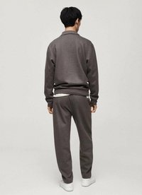 Gray sweatshirt and matching pants, made of soft fabric. Relaxed fit with ribbed cuffs and hem, worn with white sneakers.