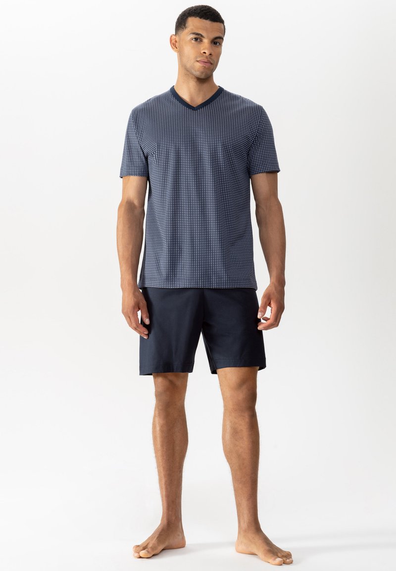 Navy V-neck T-shirt with a small geometric pattern, paired with solid dark shorts. The fabric appears lightweight and comfortable.