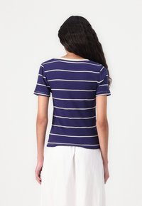 Marineblå stribet t-shirt lavet af blødt stof, med korte ærmer, en rund halsudskæring og vandrette hvide striber på ryggen.