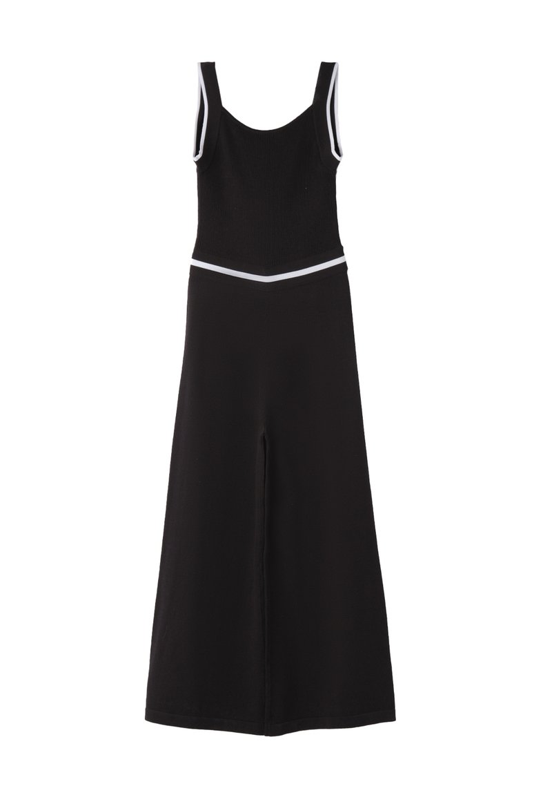 Mono negro con un cuerpo acanalado ceñido, piernas anchas y un ribete blanco contrastante a lo largo de las tirantes y la cintura. Textura suave, diseño sencillo.