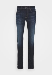 Pantalones vaqueros de mezclilla azul oscuro con un corte recto, diseño de cinco bolsillos y costuras doradas en contraste. Ligeramente descoloridos en los muslos.
