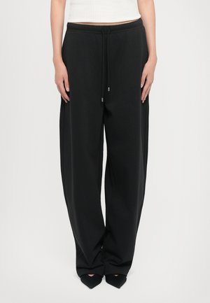 Black sweatpants with a relaxed fit, elastic waistband, and drawstring. Soft texture and side seams accentuate the wide leg design.