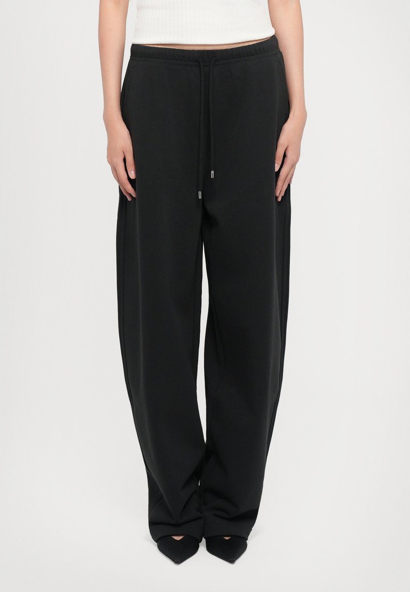 Black sweatpants with a relaxed fit, elastic waistband, and drawstring. Soft texture and side seams accentuate the wide leg design.