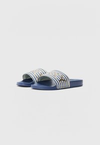 Blå sandaler med en stripe med hvite og lyseblå linjer, og en gullakcent foran. Strukturerte såler for bedre grep.