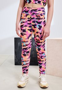 Collants colorés à imprimé léopard en rose, violet et bleu, fabriqués dans un matériau extensible avec une taille haute et une texture lisse.